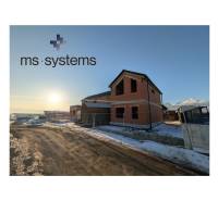 A family house in Mlynica under construction under a blue sky, with a snowy surroundings.