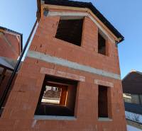An unfinished family house in the village of Mlynica with red brick walls and a sloped roof.