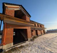An unfinished family house in Mlynica, surrounded by a snowy landscape and a blue sky.