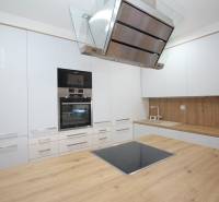 A kitchen in a 2-room apartment with white cabinets and a wooden-patterned floor.