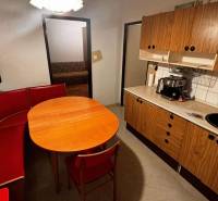 A kitchen in a 2-room apartment with a red bench and a kitchen unit with a wooden decor.
