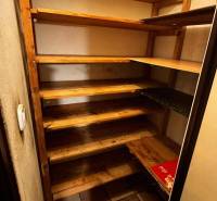Wooden shelves in the pantry of a 2-room apartment with tiles.