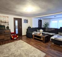 Living room in a family house with a wood-patterned floor, a sofa, and decorations.