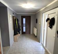 A hallway in a family house with coat racks, a radiator, and tiled flooring.