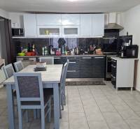 A kitchen in a family house with a dining table, kitchen unit, and appliances.