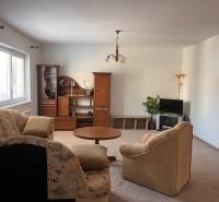 Living room in a family house with a couch, wooden furniture, and a television.