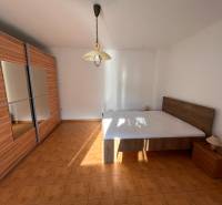 A bedroom in a family house with a large wardrobe and a bed on the floor with a wooden decor.