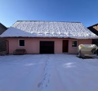 A family house in Stará Bystrica covered with snow, seating at the entrance, sunny winter day.
