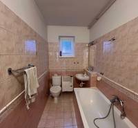 Bathroom with a bathtub and toilet in a family house, with tiles and ceramic flooring.