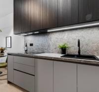 A kitchen in a 2-room apartment with dark cabinets, marble tiles, and a wooden decor floor.