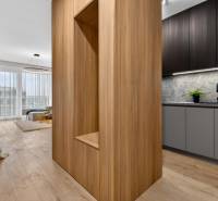 Interior of a 2-room apartment with wood-patterned flooring, a bright living room, and a kitchen.