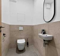 A toilet with a sink and mirror in a 2-room apartment. Beige and white tiles.
