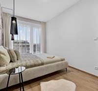 Bedroom in a 2-room apartment with a bed and wallpaper, floor with wood decor.