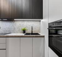 A kitchen in a 2-room apartment with a black oven and a countertop with a stone decor.