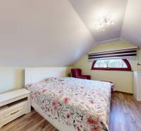 A bedroom in a family house with decorative flooring, floral bed linen, and a skylight.