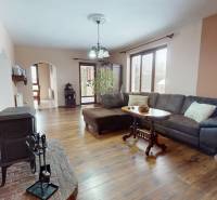 Living room in a family house with a fireplace, wooden decor flooring, and a large window.