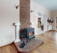 Interior of a family house with a fireplace and wood-patterned flooring.