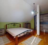 A bedroom in a family house with a metal bed and a floor with a wooden decor.
