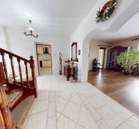 A staircase with a wooden railing, a floor with a wooden decor, a living room, a potted plant.