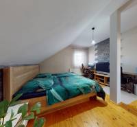 Attic bedroom in a family house with a comfortable bed and a work desk.