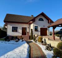 A family house in Tvrdomestice with a snowy garden and a garage, beautiful and well-maintained architecture.
