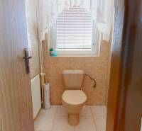 A bathroom with beige tiles and a window in a family house.
