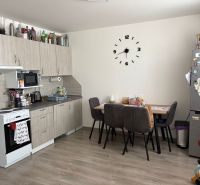 The kitchen of a 2-room apartment with a wooden decor floor, a dining table, and a kitchen unit.