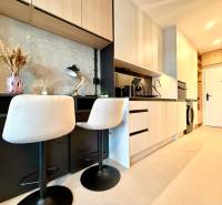 Kitchen corner in a studio apartment with bar stools and modern equipment.