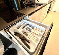 A kitchen in a studio apartment with cutlery in a drawer, a cooktop, and a sink.