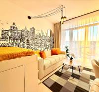 A stylish living space in a studio apartment with a wall mural and a balcony.