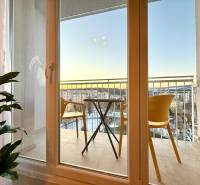 French window with a view of the balcony with chairs in a studio apartment.