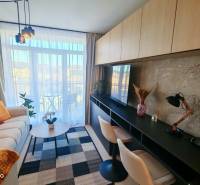 Living room in a one-bedroom apartment with a sofa, a desk, and a view of the balcony.