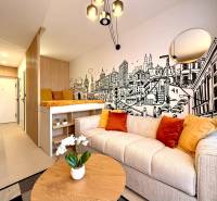 Interior of a 1-room apartment with a comfortable couch, illustrated wall, and wooden decor flooring.