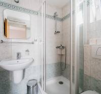Bathroom with a sink, shower, and window, complemented by white tiles and accessories.