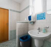 A bathroom in the office with a sink, paper dispenser, and tiles.