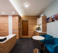 Interior of an office with a table, blue chairs, and a wooden-patterned floor.