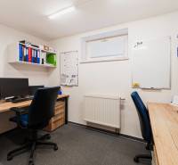 Offices with desks, computers, and shelves with binders, floor with wood decor.