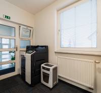Offices with a multifunction printer, shredder, radiator, and carpet with subtle patterns.