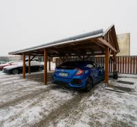 Parked cars in a snowy parking lot with a shelter on Bratislavská Street in Trenčín.