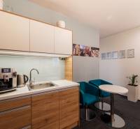 Offices with a kitchenette, coffee maker, sink, blue armchairs, and decorative certificates on the wall.