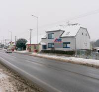 A snowy Bratislavská cesta in Trenčín with offices and passing cars.