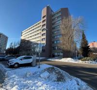 An office building in Poprad surrounded by snow and parked cars.