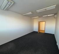 Office room with dark carpet, white walls, and ceiling lighting.