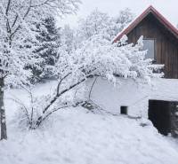 A snow-covered family house in the village of Stará Huta on Stará Huta 84 street surrounded by trees.