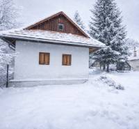A snow-covered family house on Stará Huta 84 street in the village of Stará Huta surrounded by trees.