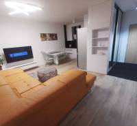 Living room in a two-room apartment with a yellow sofa and a wooden decor floor.