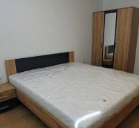 Bedroom with a bed, dresser, and wardrobe in a 3-room apartment, floor with wood decor.