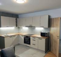 A kitchen in a 3-room apartment with a kitchen unit and a wooden decor floor.