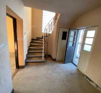 Interior of a family house with a concrete floor, stairs, and open doors.