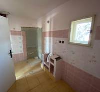 A room in a family house with pink tiles, a small window, and a yellow floor.